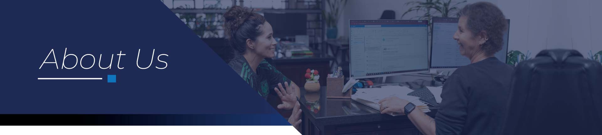 Two smiling mortgage professionals collaborating at an office desk with dual monitors at Direct Capital Lending, highlighting expert teamwork and personalized home loan services under the "About Us" banner.