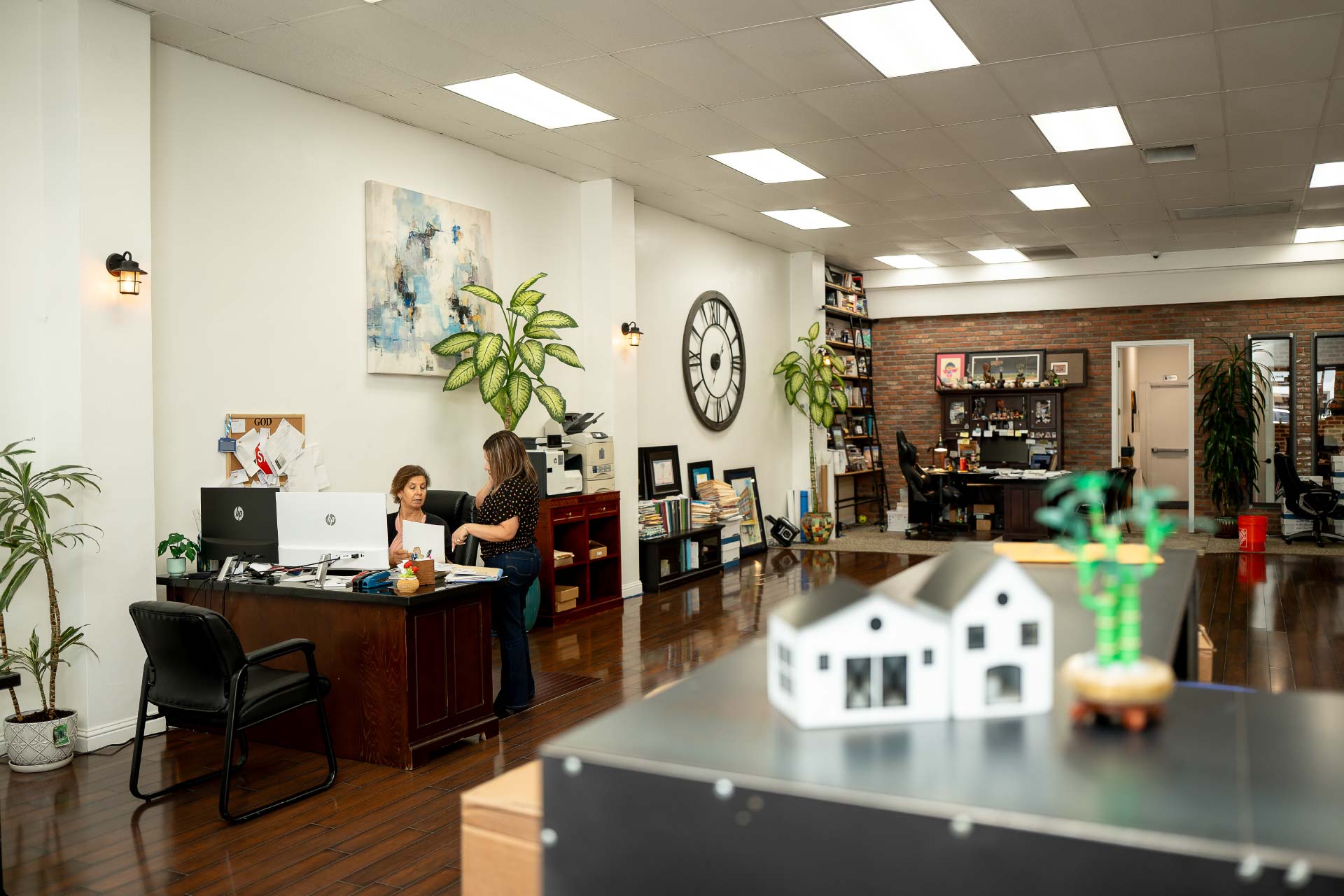A wide, interior view of the spacious and welcoming Direct Capital Lending office, featuring a clean workspace, a small model house on display, and team members assisting clients.