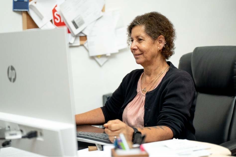 A professional female team member at Direct Capital Lending smiling while working on a computer, demonstrating dedicated client support and local mortgage assistance.
